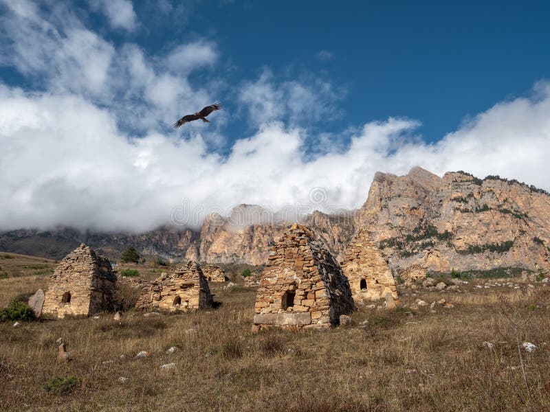 A kite flies over a grave crypt. Old stone tomb, a crypt on the top of a mountain. Old Ossetian family crypt in the misty mountains. A kite flies over a grave crypt. Old stone tomb, a crypt on the top of a mountain. Old Ossetian family crypt in the misty mountains