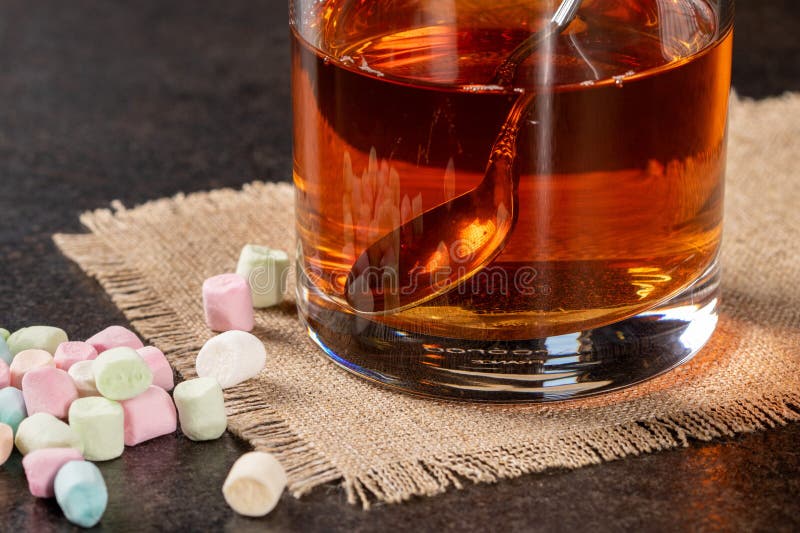 A glass of tea on a napkin and scattered marshmallows. A glass of tea on a napkin and scattered marshmallows.