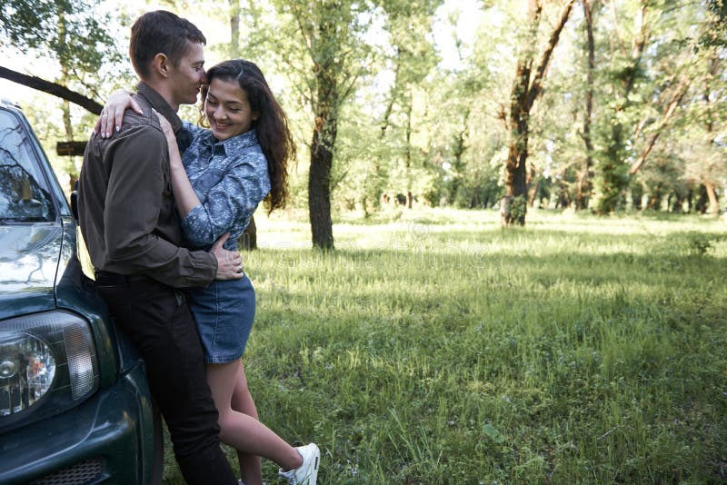 Una coppia che sta vicino all'automobile nella foresta, nelle sensibilità romantiche e nell'amore immagini stock Una coppia che sta vicino all'automobile nella foresta, nelle sensibilità romantiche e nell'amore immagini stock