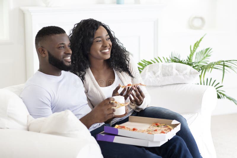 Day off at home. Black family couple eating pizza and drinking coffee, spending weekend together. Day off at home. Black family couple eating pizza and drinking coffee, spending weekend together.