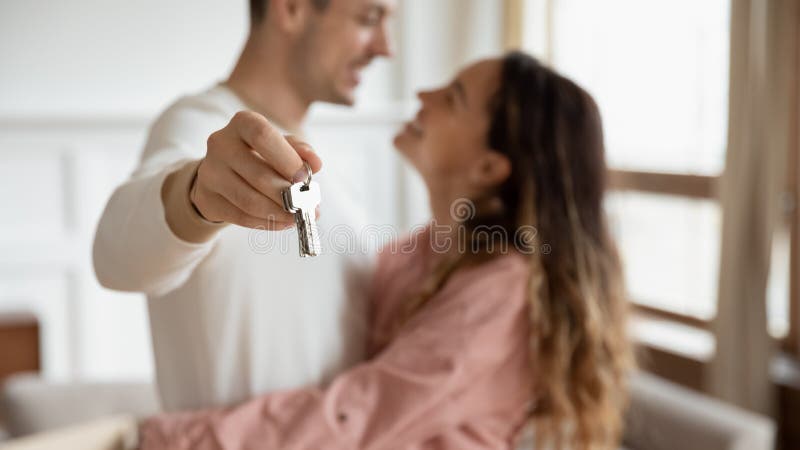 Una coppia felice abbracciando le chiavi di tenuta compra il nuovo concetto di appartamento, chiudi