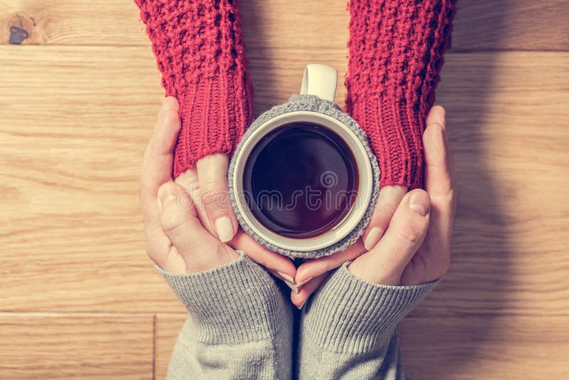 Una coppia in mani di riscaldamento di amore con una tazza calda di tè immagine stock Una coppia in mani di riscaldamento di amore con una tazza calda di tè immagine stock