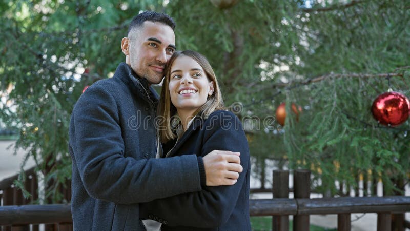 Una coppia sorridente abbraccia all'aperto con decorazioni festive che trasmettono amore e condivisione immagine stock libera da diritti