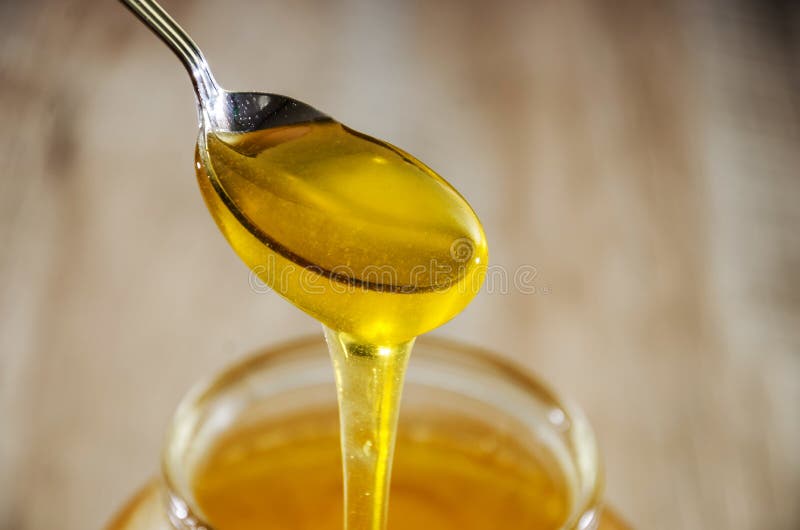 Una cucchiaiata di miele dolce e fresco Miele in un cucchiaio su un fondo del barattolo Primo piano Mielate da un cucchiaio in un immagine stock libera da diritti Una cucchiaiata di miele dolce e fresco Miele in un cucchiaio su un fondo del barattolo Primo piano Mielate da un cucchiaio in un immagine stock libera da diritti