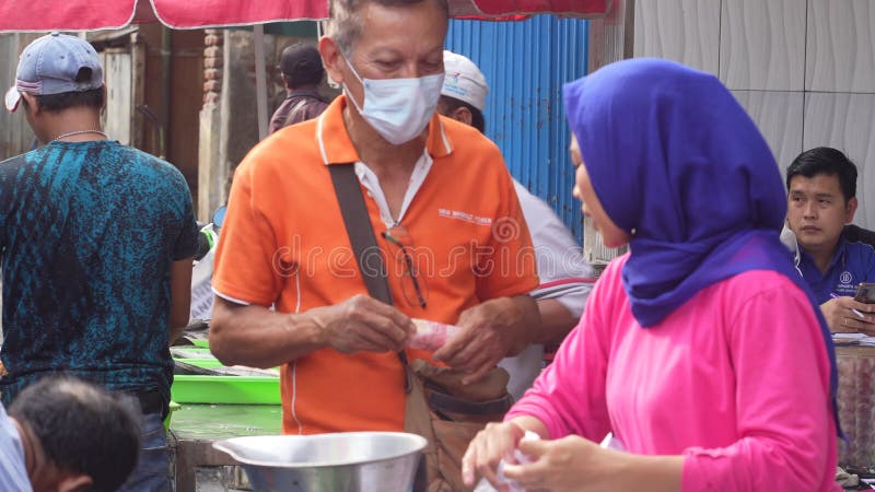Una dama sirviendo a un cliente comprando gambas frescas en el mercado tradicional de surabaya indonesia.