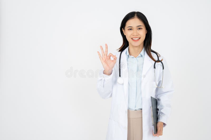 Una doctora con confianza mostrando el signo de la mano correcta mirando con confianza el fondo blanco de la cámara imagen de archivo