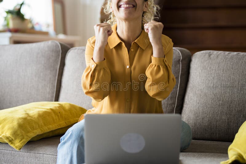 Una donna adulta felice riceve notifica sul computer portatile e festeggia con gioia le donne che a casa godono della tecnologia o. Le donne adulte felici ricevono la notifica sul computer portatile e festeggiano con gioia le donne a casa approfittando della tecnologia online, sorprende la donna di mezza età seduta sul divano per ricevere notizie sul quaderno del pc