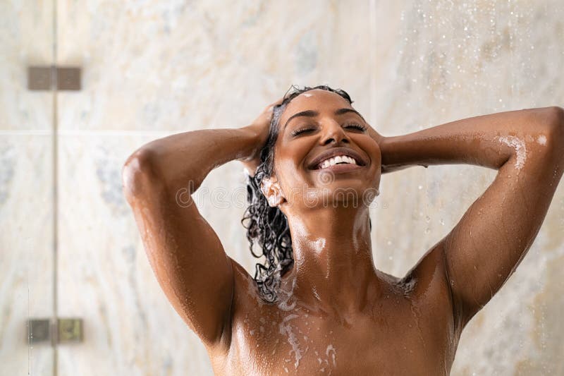 Una donna africana che lava i capelli sotto la doccia