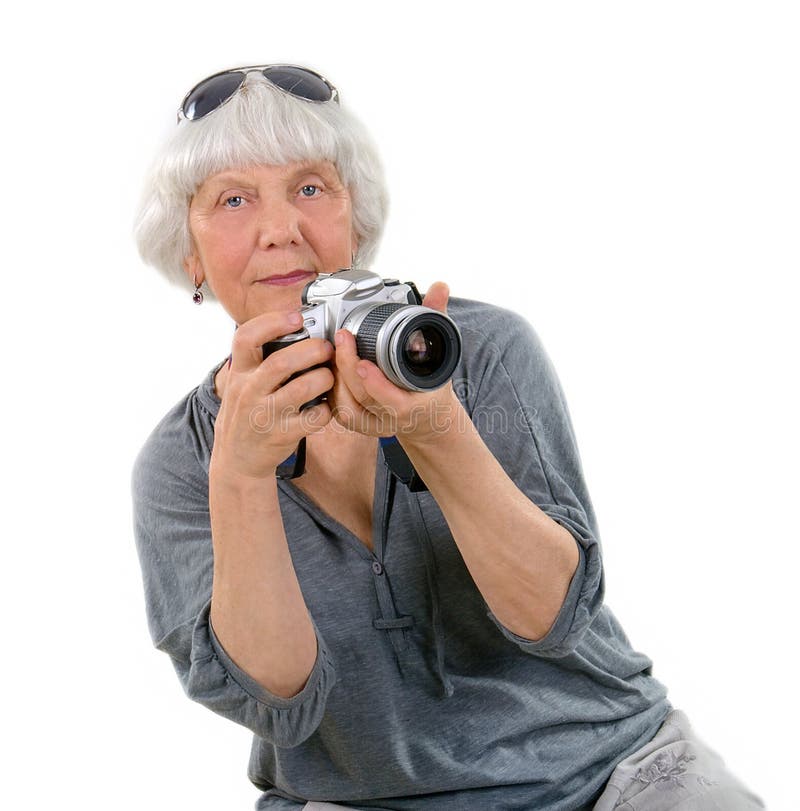 Una donna anziana e felice che scatta foto con una telecamera su sfondo bianco. pensione attiva. tempo libero e passatempi