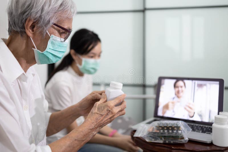 Una donna anziana malata che fa una videochiamata con un dottore su un computer portatile mentre sta a casa un paziente anziano ch