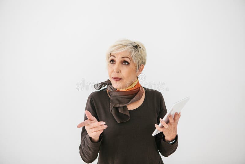 Una donna anziana moderna positiva tiene una compressa in sue mani e la usa La più vecchia generazione e la tecnologia moderna fotografia stock libera da diritti Una donna anziana moderna positiva tiene una compressa in sue mani e la usa La più vecchia generazione e la tecnologia moderna fotografia stock libera da diritti