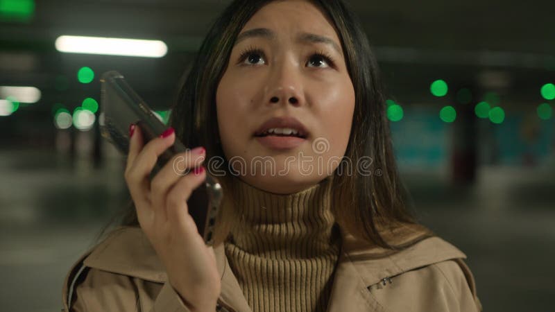 Una donna asiatica irritata ha detto al telefono con una ragazza cinese mentre parla mentre parcheggia smartphone