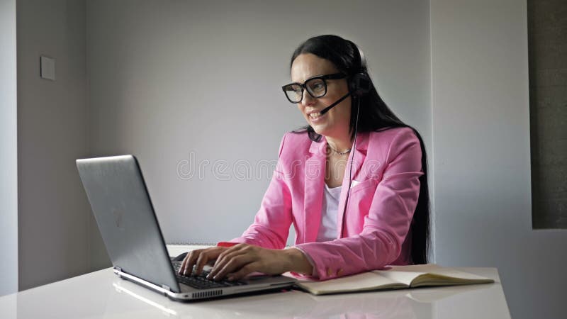 Una donna attraente lavora al computer in ufficio. comunica amichevolmente con il cliente e scrive qualcosa