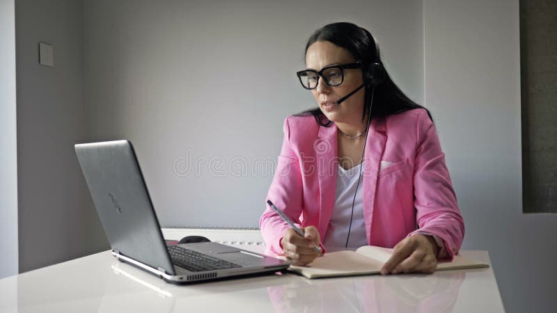 Una donna attraente lavora al computer in ufficio. comunica amichevolmente con il cliente e scrive qualcosa