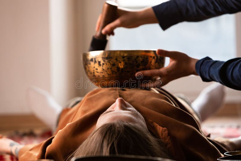 Woman making relaxing massage, meditation, sound therapy with tibetian singing bowls. Stress relief. Selective focus. Bottom view. Woman making relaxing massage, meditation, sound therapy with tibetian singing bowls. Stress relief. Selective focus. Bottom view.