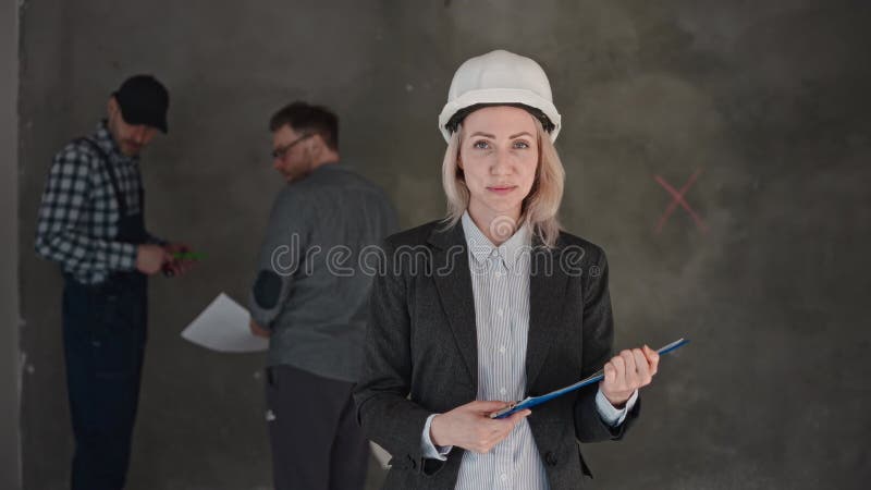 Una donna con un cappello duro sorride in una stanza con due uomini ad un evento formale video d archivio