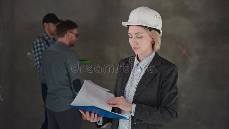 Una donna con un cappello fisso che tiene in mano un portablocco mentre rivede i documenti video d archivio