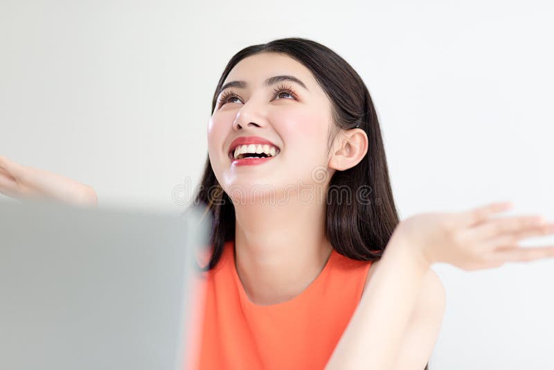 Una donna d'affari asiatica di successo indossa una camicetta arancione senza maniche che lavora con il portatile e una tazza di immagini stock Una donna d'affari asiatica di successo indossa una camicetta arancione senza maniche che lavora con il portatile e una tazza di immagini stock
