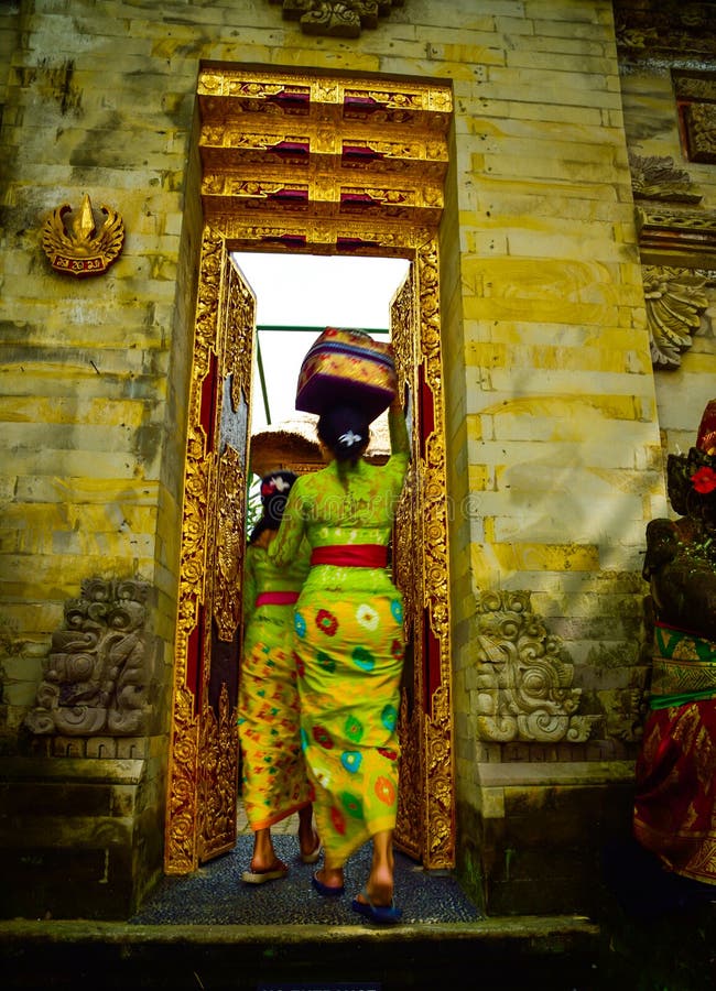 Una donna di balinese che indossa abbigliamento locale tradizionale che entra in un tempio sacro fotografie stock libere da diritti Una donna di balinese che indossa abbigliamento locale tradizionale che entra in un tempio sacro fotografie stock libere da diritti