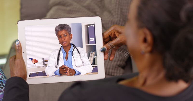 Una donna di colore più anziana che parla con suo medico afroamericano via la video chiacchierata