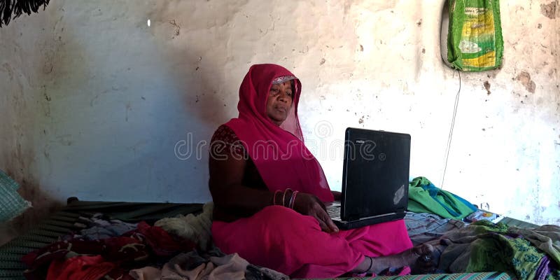 Una donna di un villaggio indiano che gestisce un computer portatile seduto alla culla