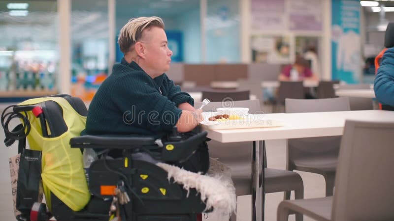 Una donna disabile seduta a tavola nella sala da pranzo mangia