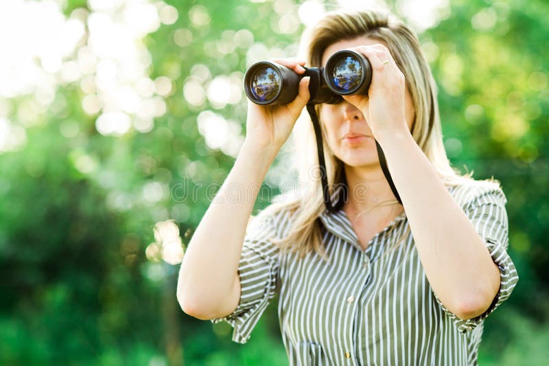 Una donna guarda tramite il binocolo all'aperto in foresta fotografia stock Una donna guarda tramite il binocolo all'aperto in foresta fotografia stock
