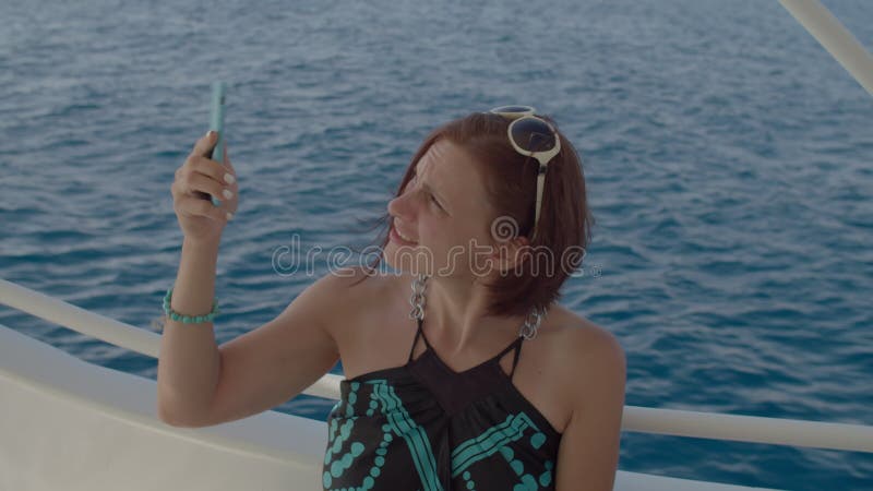Una donna infastidita che cerca di trovare una rete mobile su una barca a vela con lo smartphone. persona alla ricerca del segnale