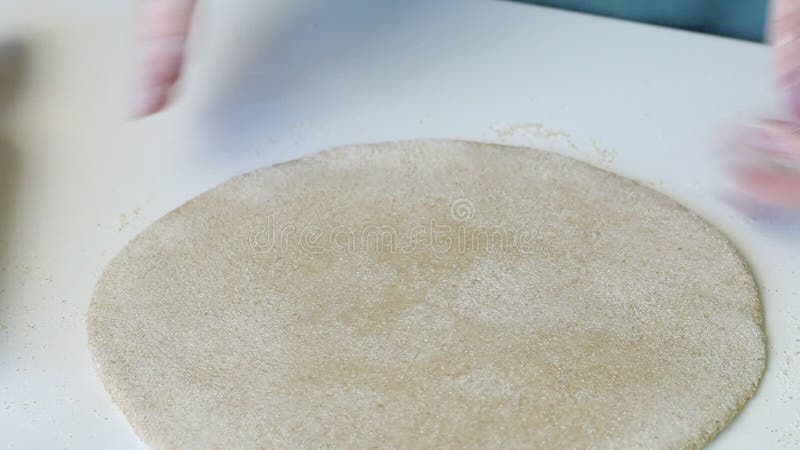 Una donna le dà una forma rotonda di una torta rovesciata da un pezzo di impasto. prepara una tortilla fresca. chiusura