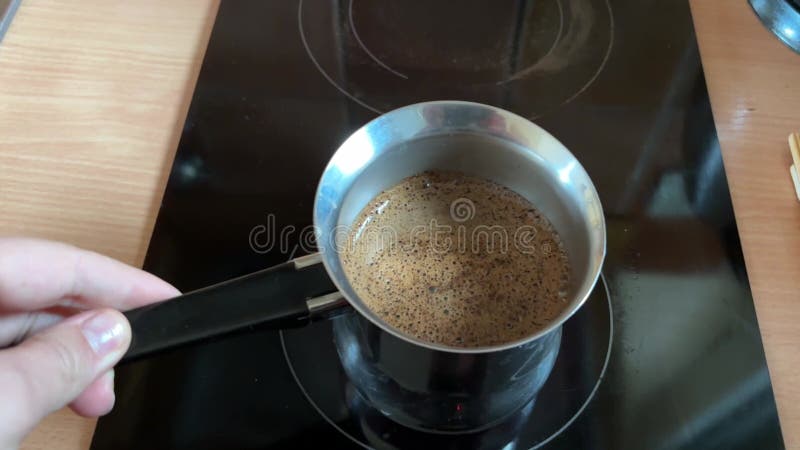 Una donna prepara il caffè in un caffè in un cielo su una pentola elettrica catturando calore e rituali del caffè fatto in casa archivi video