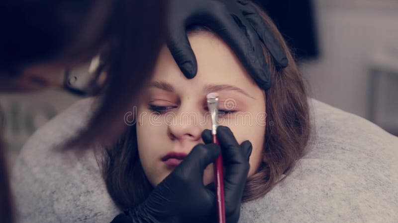 Una donna professionista sulle sopracciglia disegna le sopracciglia al cliente in un salone di bellezza.