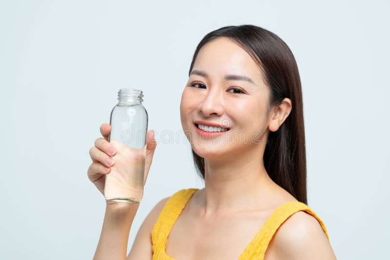 Una donna sorridente con una bottiglia d'acqua di vetro. promuovere la salute dell'idratazione e la vita ecocompatibile fotografie stock