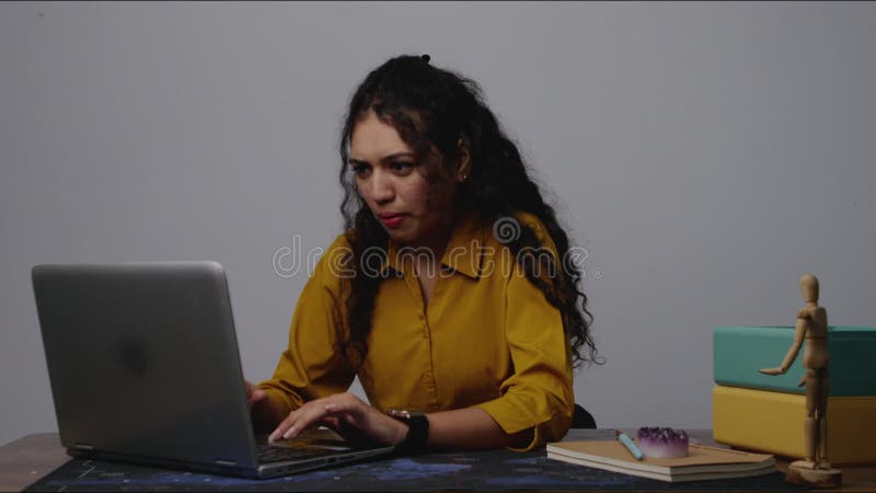Una donna sudasiatica concentrata che scrive sul suo computer portatile in un ufficio che si concentra sullo schermo stock footage