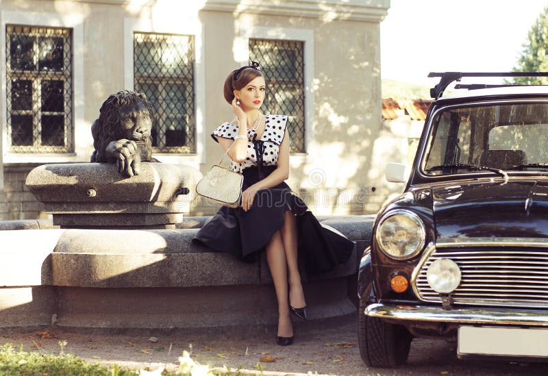 Una donna in un retro vestito che posa vicino ad un'automobile immagini stock Una donna in un retro vestito che posa vicino ad un'automobile immagini stock