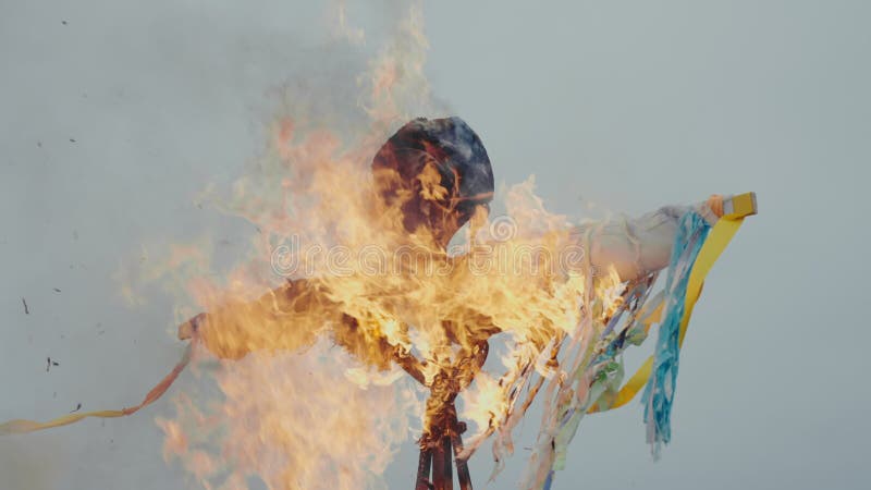 Una efigie de maslenitsa arde en un fuerte fuego contra un cielo azul turbio. la fiesta pagana de la maslenitsa y la