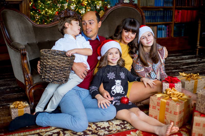 Una famiglia di Natale di cinque genti, dei genitori felici e dei loro bambini fotografia stock Una famiglia di Natale di cinque genti, dei genitori felici e dei loro bambini fotografia stock