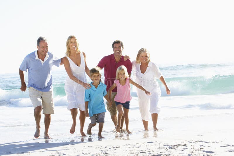 Una famiglia di tre generazioni su funzionamento di festa lungo la spiaggia