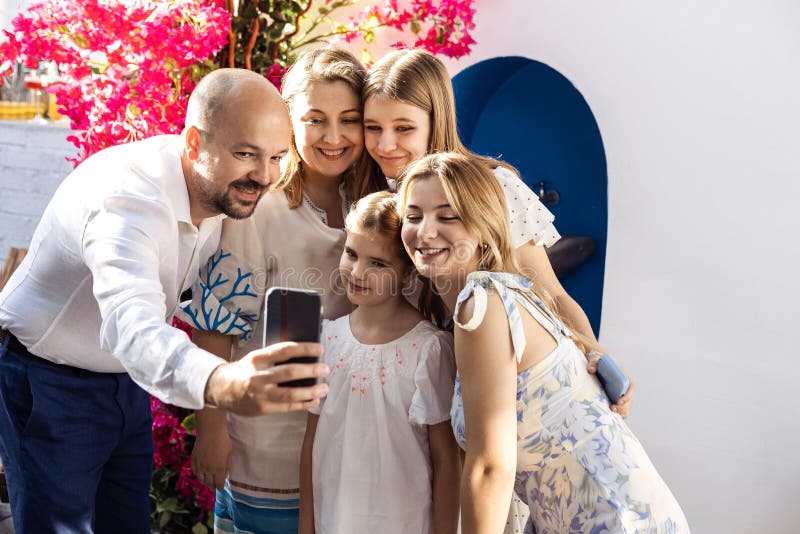 Una famiglia felice viene fotografata durante un evento festivo. Un uomo gioioso si fa un selfie con le sue tre figlie e sua mogli immagine stock libera da diritti