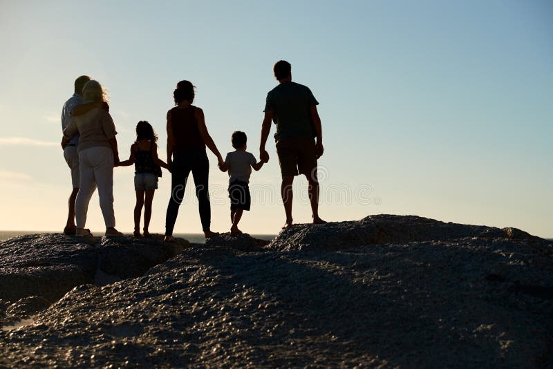 Una famiglia su una spiaggia che si tiene per mano, vista piena d'ammirazione, integrale, siluetta, vista posteriore di tre gener