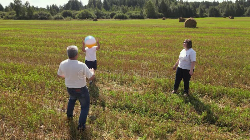 Una familia feliz con camisetas blancas que juegan al balón alegre y divertido. almacen de metraje de vídeo