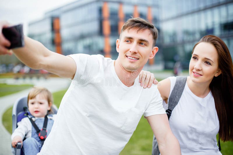 Una familia feliz hace el selfie en un smartphone mientras que camina en las bicicletas en el verano imágenes de archivo libres de regalías Una familia feliz hace el selfie en un smartphone mientras que camina en las bicicletas en el verano imágenes de archivo libres de regalías