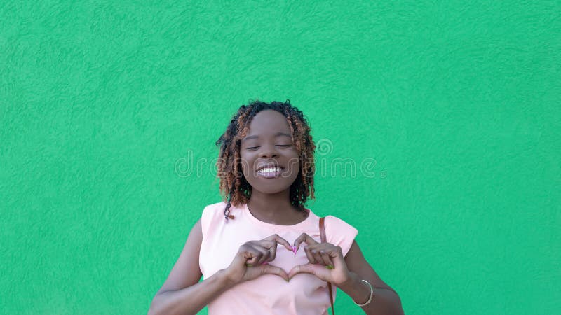 Una feliz mujer africanamericana con un fondo verde. amar. gestos. emociones positivas fotos de archivo libres de regalías
