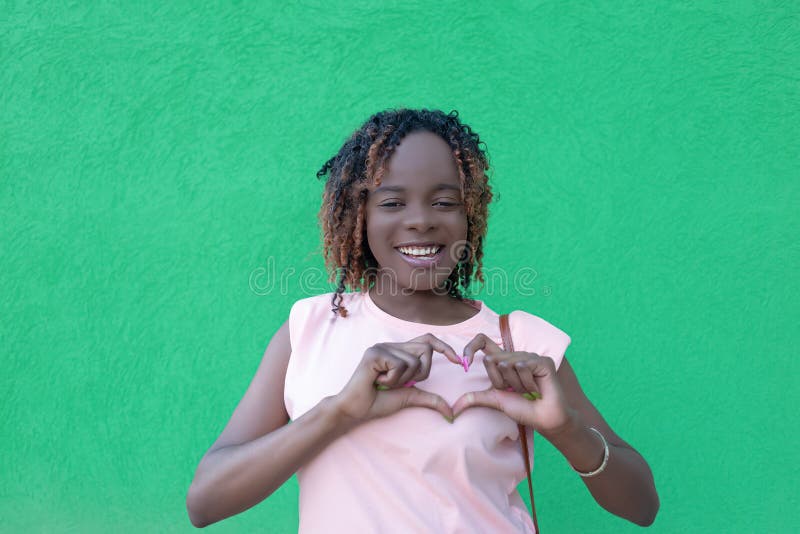 Una feliz mujer africanamericana con un fondo verde. amar. gestos. emociones positivas fotos de archivo libres de regalías