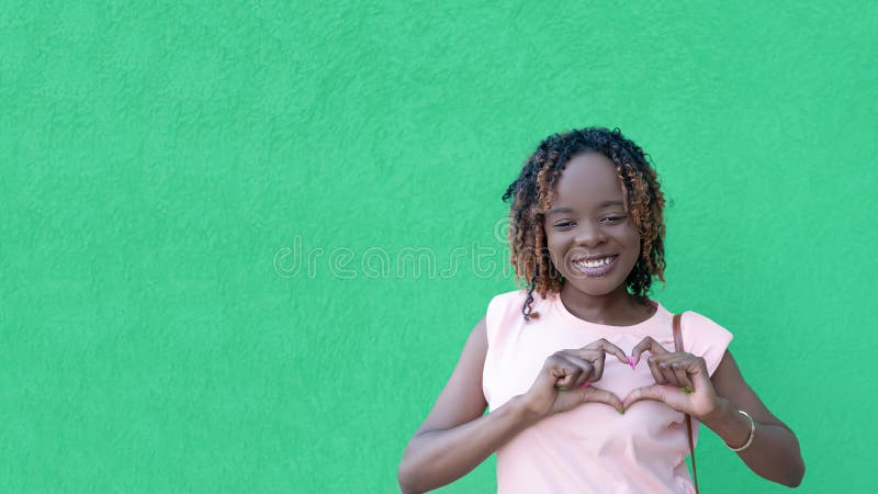Una feliz mujer africanamericana con un fondo verde. amar. gestos. espacio de copia. Mujer feliz sonriente con un fondo verde.
