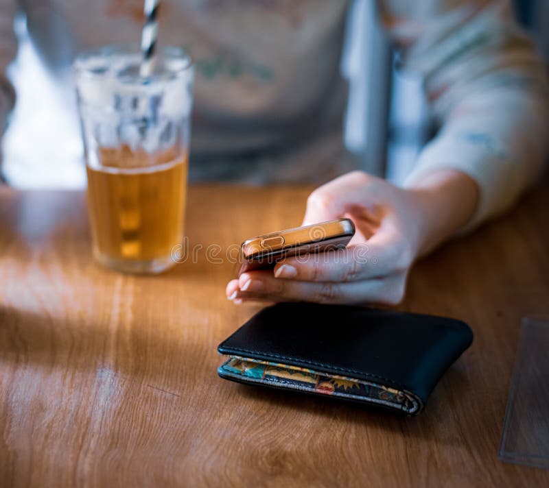 Una femmina bianca si ? seduta la birra di zenzero gi? bevente mentre sul suo telefono cellulare in un ambiente luminoso fotografie stock Una femmina bianca si ? seduta la birra di zenzero gi? bevente mentre sul suo telefono cellulare in un ambiente luminoso fotografie stock