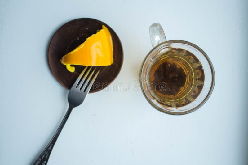 Una fetta di torta deliziosa del limone con tè su un fondo bianco fotografia stock Una fetta di torta deliziosa del limone con tè su un fondo bianco fotografia stock