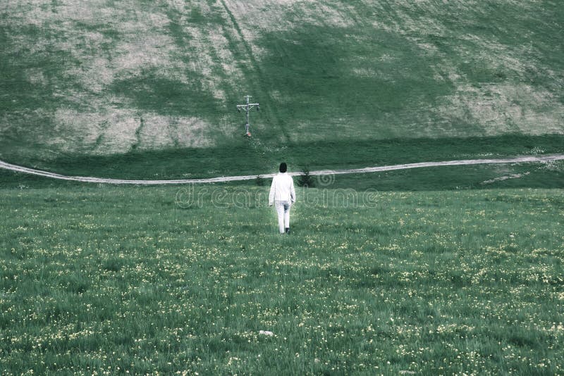 Una figura d'ardore bianca sola di un uomo cammina attraverso il gr triste fotografie stock Una figura d'ardore bianca sola di un uomo cammina attraverso il gr triste fotografie stock