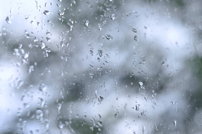 Una foto de la lluvia cae en el vidrio de la ventana con una vista borrosa de los árboles verdes florecientes El mostrar abstract fotografía de archivo libre de regalías Una foto de la lluvia cae en el vidrio de la ventana con una vista borrosa de los árboles verdes florecientes El mostrar abstract fotografía de archivo libre de regalías