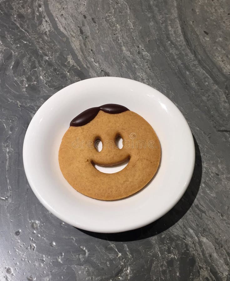 Una galleta de la sonrisa en la placa blanca en la tabla de mármol foto de archivo libre de regalías Una galleta de la sonrisa en la placa blanca en la tabla de mármol foto de archivo libre de regalías