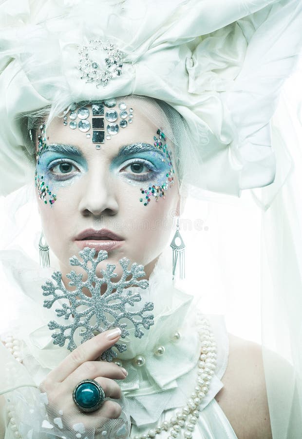 Una giovane bellissima donna con trucco creativo in stile nuovo anno tiene in mano dei fiocchi di neve d'argento vicino al suo vol fotografie stock libere da diritti